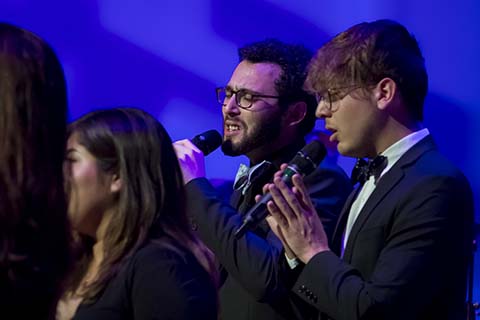 Two men in suits holding microphones are performing at an event